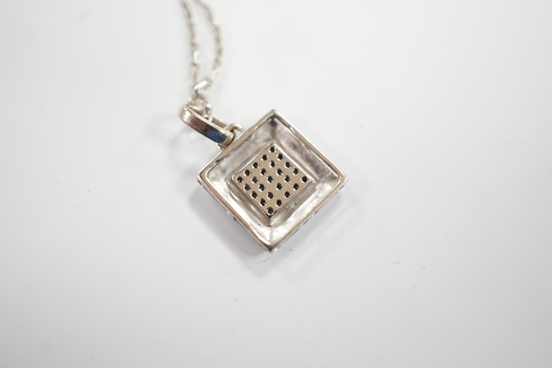 A modern Italian 18k white metal and diamond chip set pendant, on an 18k chain, 42cm and a white metal and diamond chip set square cluster pendant on an 18k chain, gross weight 6 grams.